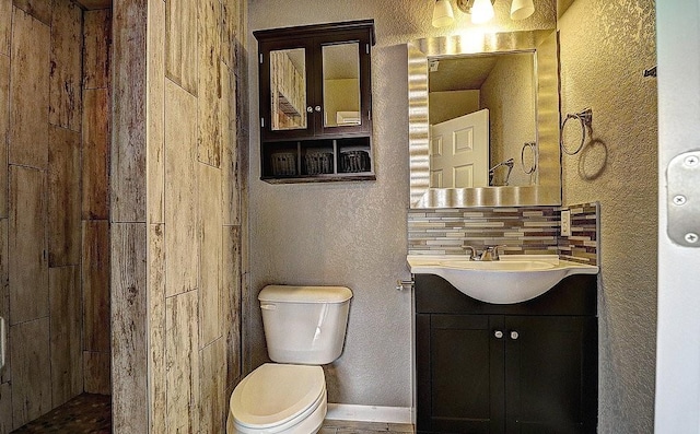 bathroom featuring vanity, toilet, and decorative backsplash