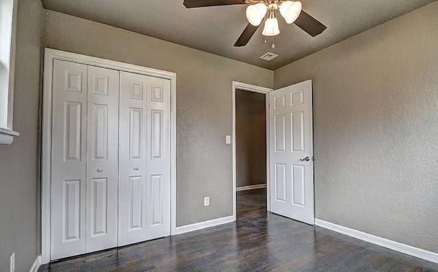 unfurnished bedroom featuring dark wood-type flooring, a closet, and ceiling fan