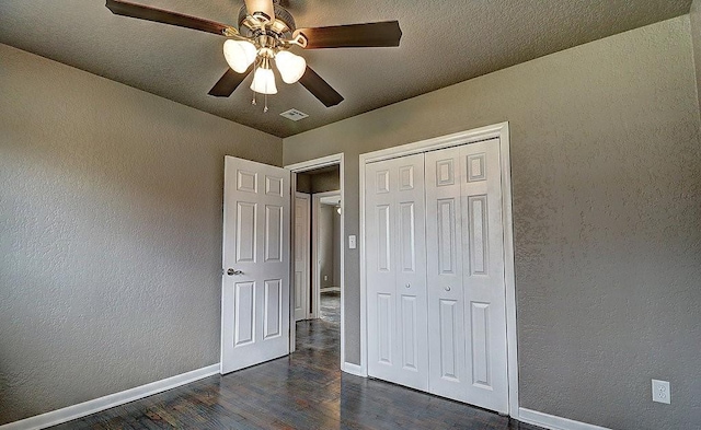 unfurnished bedroom with a textured ceiling, dark wood-type flooring, a closet, and ceiling fan