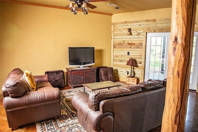 living room featuring tile patterned flooring, crown molding, ceiling fan, and wood walls