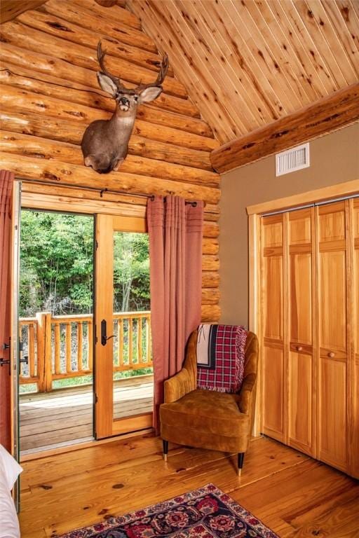 sitting room with light hardwood / wood-style flooring, high vaulted ceiling, rustic walls, and plenty of natural light