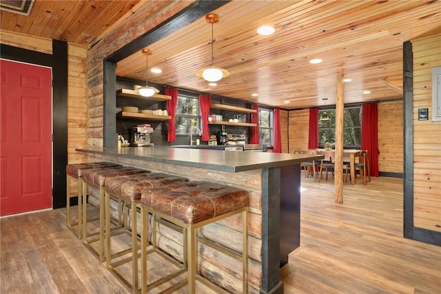 bar with wooden walls, decorative light fixtures, sink, light hardwood / wood-style floors, and wooden ceiling