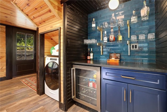 bar with wood ceiling, blue cabinetry, wooden walls, wine cooler, and washer / clothes dryer