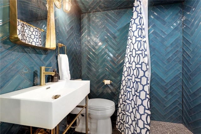 bathroom featuring toilet, sink, and tile walls