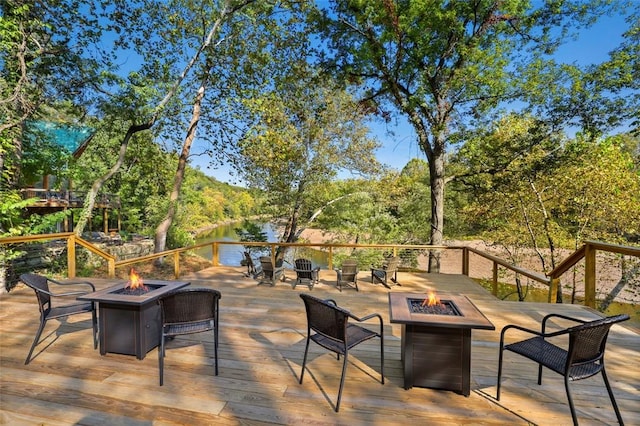 wooden deck featuring a water view and a fire pit