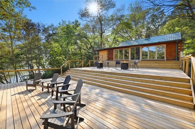 wooden terrace featuring a water view and an outdoor fire pit