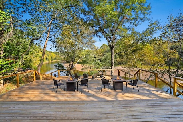 wooden terrace featuring a water view and a fire pit