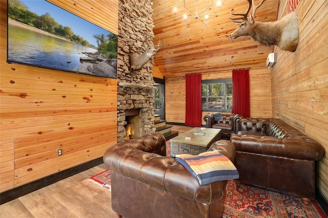 living room featuring hardwood / wood-style flooring, a towering ceiling, wooden walls, and a stone fireplace