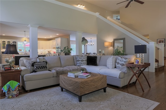 living room with decorative columns, hardwood / wood-style floors, ceiling fan with notable chandelier, and plenty of natural light