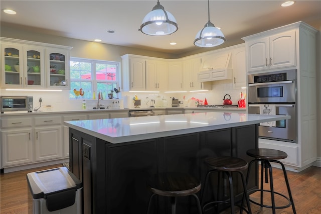 kitchen with white cabinetry, appliances with stainless steel finishes, hardwood / wood-style flooring, and a center island