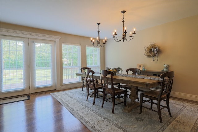 dining space with hardwood / wood-style floors and a notable chandelier