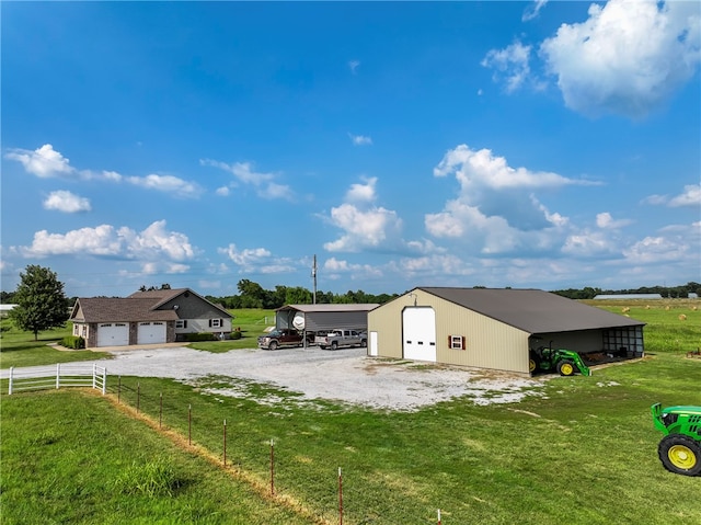 rear view of property with a garage, a lawn, an outbuilding, and a rural view