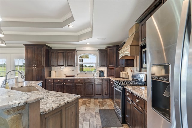 kitchen featuring stainless steel fridge with ice dispenser, tasteful backsplash, range with gas stovetop, and plenty of natural light