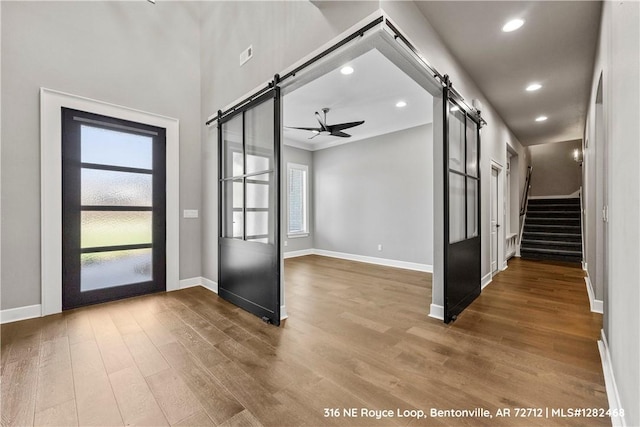 foyer entrance with hardwood / wood-style floors, a barn door, and ceiling fan