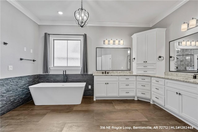 bathroom with vanity, crown molding, a bath, and a chandelier