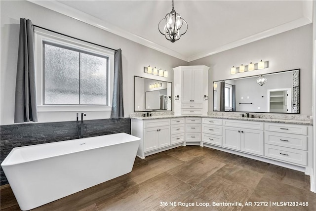 bathroom featuring a washtub, vanity, an inviting chandelier, and crown molding