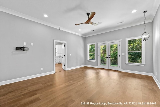 interior space with french doors, ceiling fan with notable chandelier, crown molding, and hardwood / wood-style floors