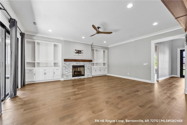 unfurnished living room with a fireplace, wood-type flooring, ceiling fan, and crown molding