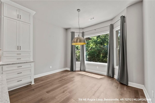 unfurnished dining area featuring plenty of natural light and dark hardwood / wood-style floors