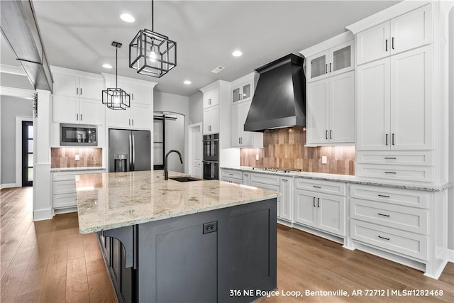 kitchen with a spacious island, sink, white cabinets, and black appliances