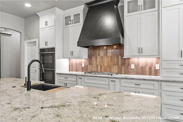 kitchen with sink, stainless steel gas cooktop, tasteful backsplash, white cabinets, and custom range hood