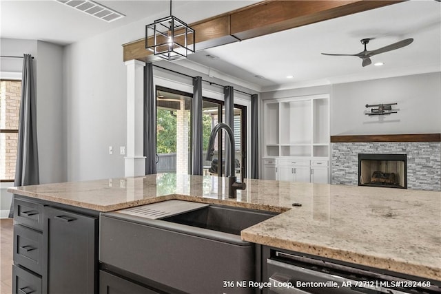 kitchen with a stone fireplace, light stone countertops, dishwasher, and hanging light fixtures