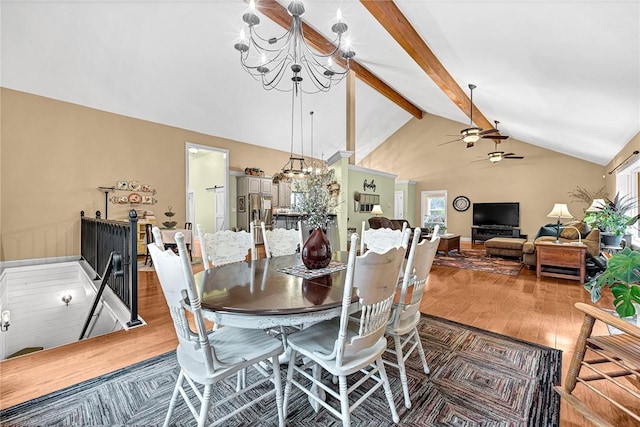 dining room featuring ceiling fan with notable chandelier, wood-type flooring, high vaulted ceiling, and beamed ceiling