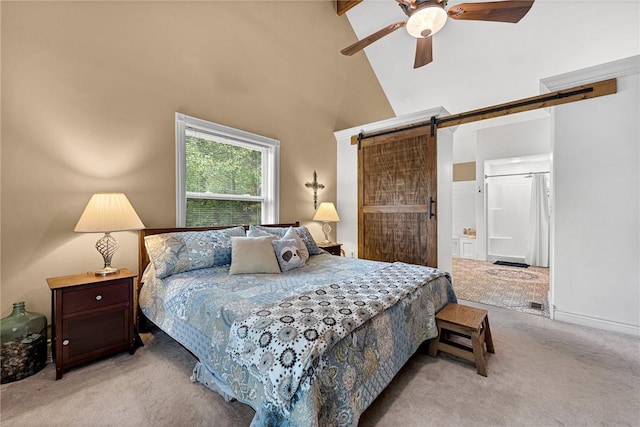 carpeted bedroom with ceiling fan, ensuite bathroom, a barn door, and high vaulted ceiling