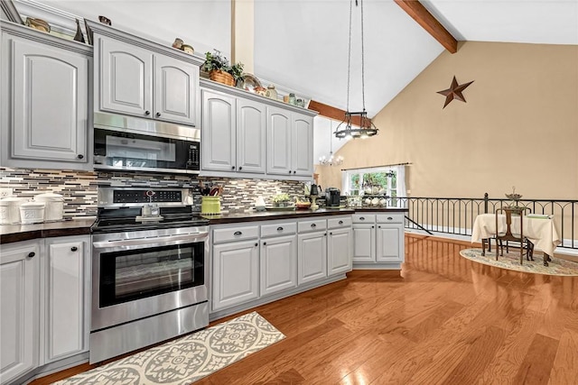 kitchen featuring decorative light fixtures, backsplash, light hardwood / wood-style floors, stainless steel appliances, and beam ceiling