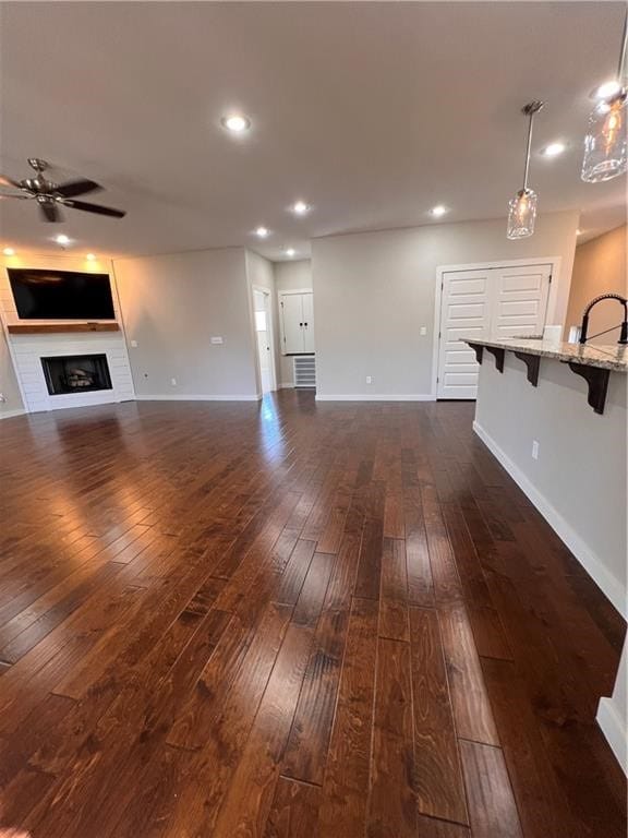 unfurnished living room featuring sink, dark hardwood / wood-style floors, and ceiling fan