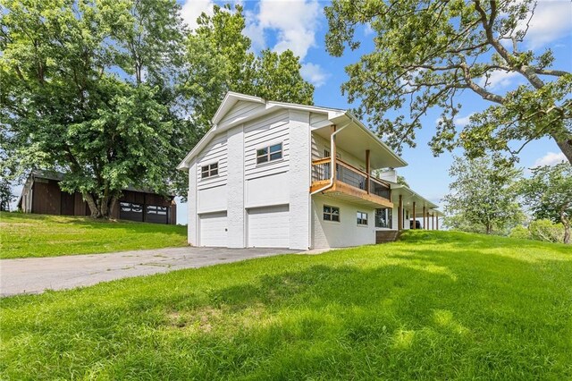 view of side of property with a balcony, a garage, and a yard