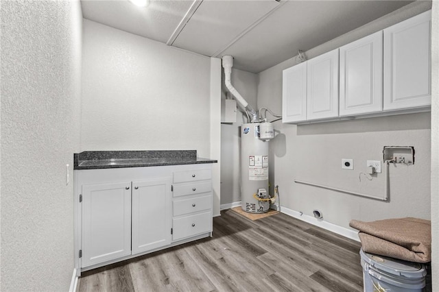 clothes washing area with cabinets, washer hookup, gas water heater, wood-type flooring, and hookup for an electric dryer