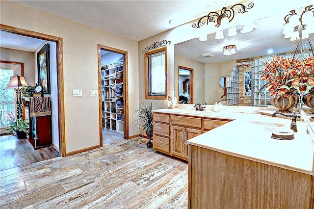 full bathroom with baseboards, a walk in closet, wood finished floors, and vanity