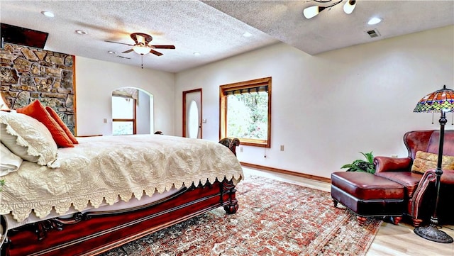 bedroom featuring arched walkways, recessed lighting, a textured ceiling, wood finished floors, and baseboards