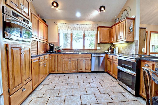 kitchen featuring brown cabinetry, tasteful backsplash, stainless steel appliances, and a sink