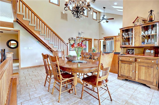 dining room with ceiling fan with notable chandelier, a skylight, visible vents, baseboards, and stairway