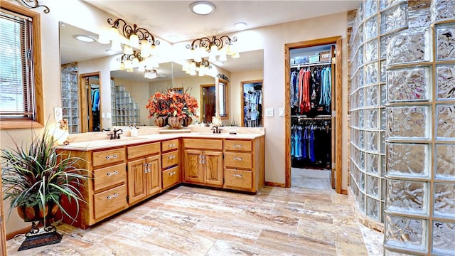 bathroom featuring a walk in closet, a sink, and double vanity