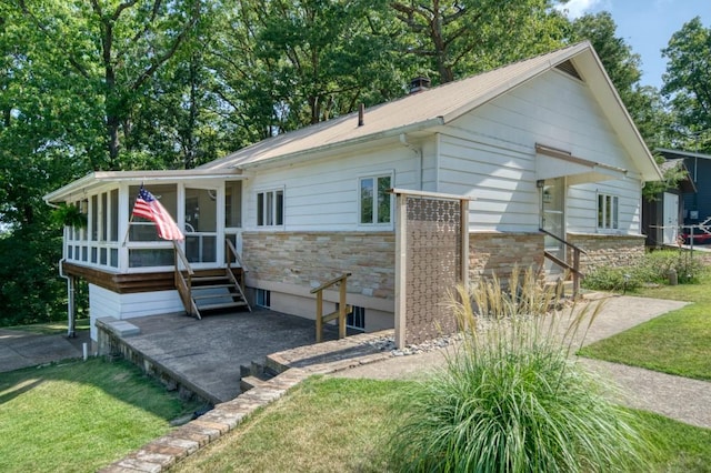 view of front facade featuring stone siding, a sunroom, and a front yard