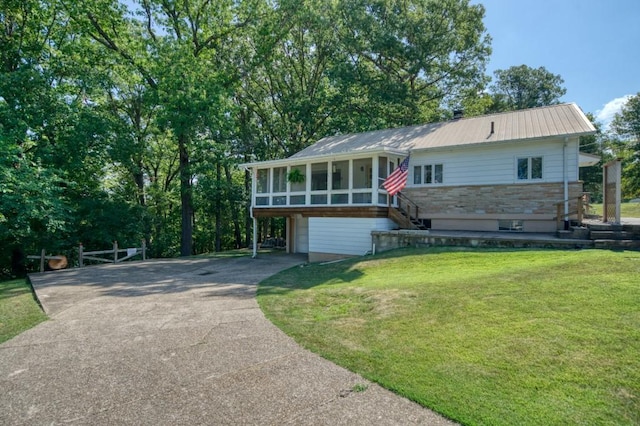 ranch-style house with a sunroom, stone siding, metal roof, aphalt driveway, and a front yard