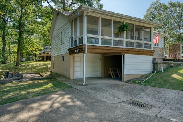 view of front of home with a garage, a front yard, a sunroom, and concrete driveway