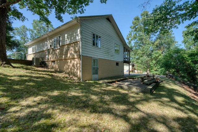 view of side of home with a lawn, a patio area, and central air condition unit