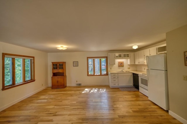 kitchen with white appliances, a sink, white cabinetry, light countertops, and light wood finished floors