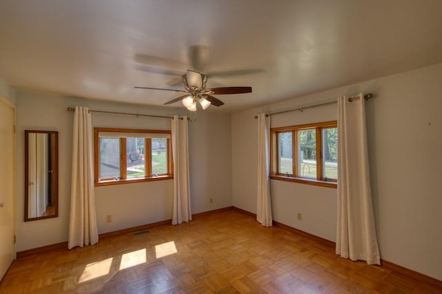 spare room featuring visible vents, ceiling fan, a wealth of natural light, and baseboards