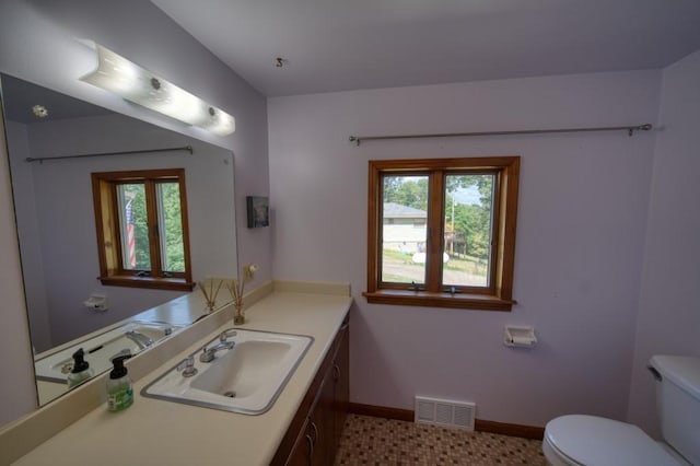 bathroom with toilet, vanity, visible vents, and baseboards