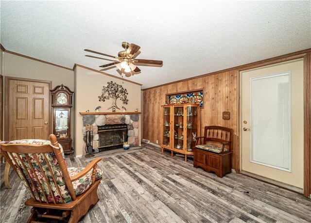 living room with a stone fireplace, ceiling fan, a textured ceiling, and hardwood / wood-style flooring