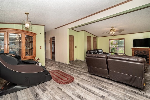 living room with crown molding, a stone fireplace, a textured ceiling, and wood finished floors