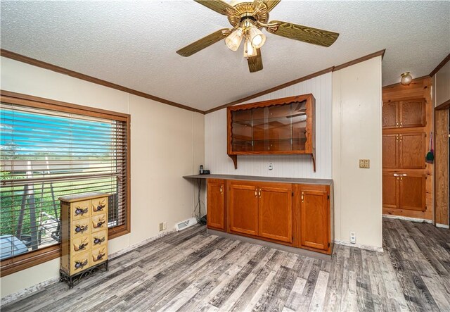 interior space with ceiling fan, a textured ceiling, hardwood / wood-style flooring, and ornamental molding