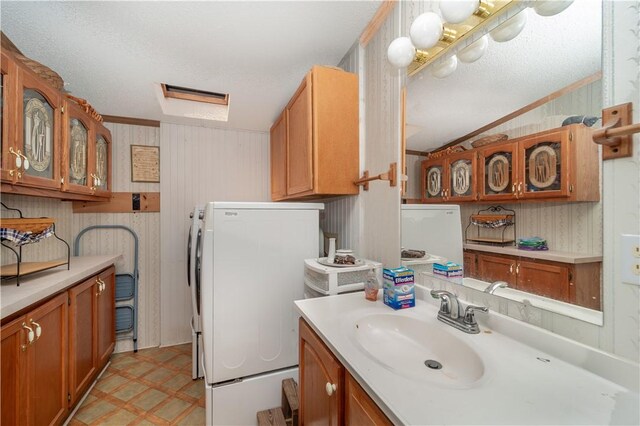 bathroom with lofted ceiling, a textured ceiling, tile patterned floors, sink, and ornamental molding