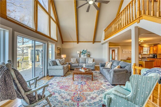 living room with ceiling fan, high vaulted ceiling, light wood-type flooring, and beamed ceiling