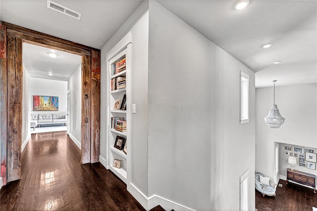 corridor with built in shelves and dark hardwood / wood-style flooring